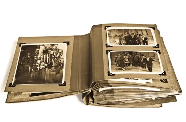 An open vintage photo album with black-and-white family photographs mounted on its pages