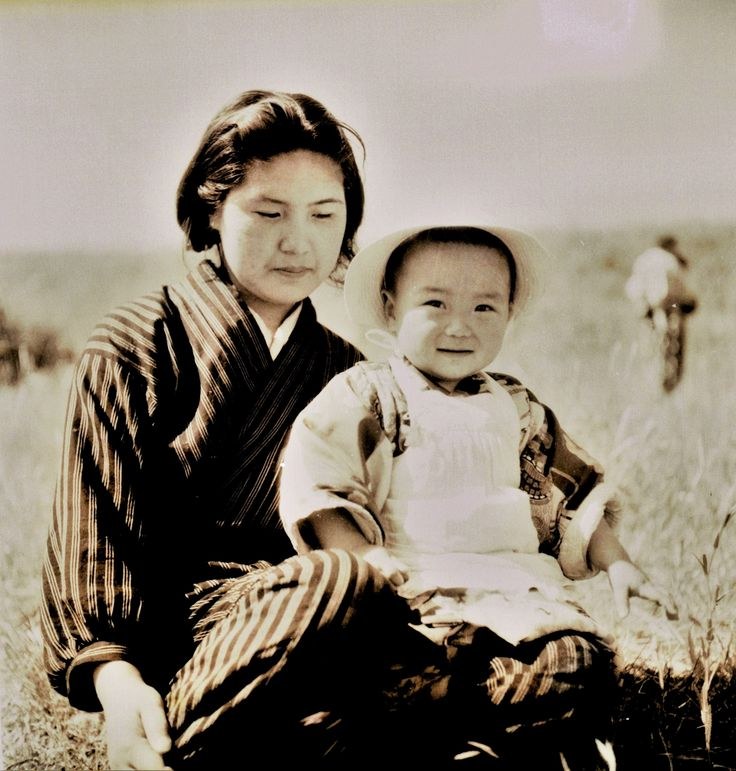Sepia photograph of a woman in a striped kimono with a small child in a sun hat
