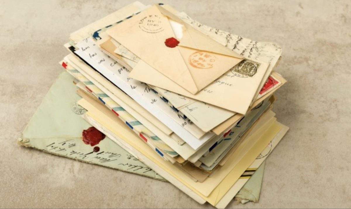 A stack of old handwritten letters and envelopes, one sealed with a red wax stamp