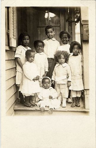 Vintage photograph of seven children posed together on a porch